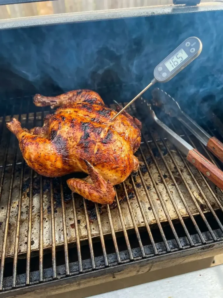 Checking the internal temperature of smoked whole chicken with a meat thermometer
